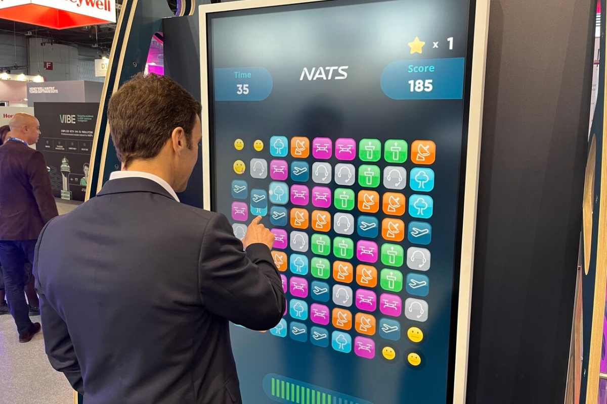 Person Playing Match-3 Game on Large Touchscreen at Event